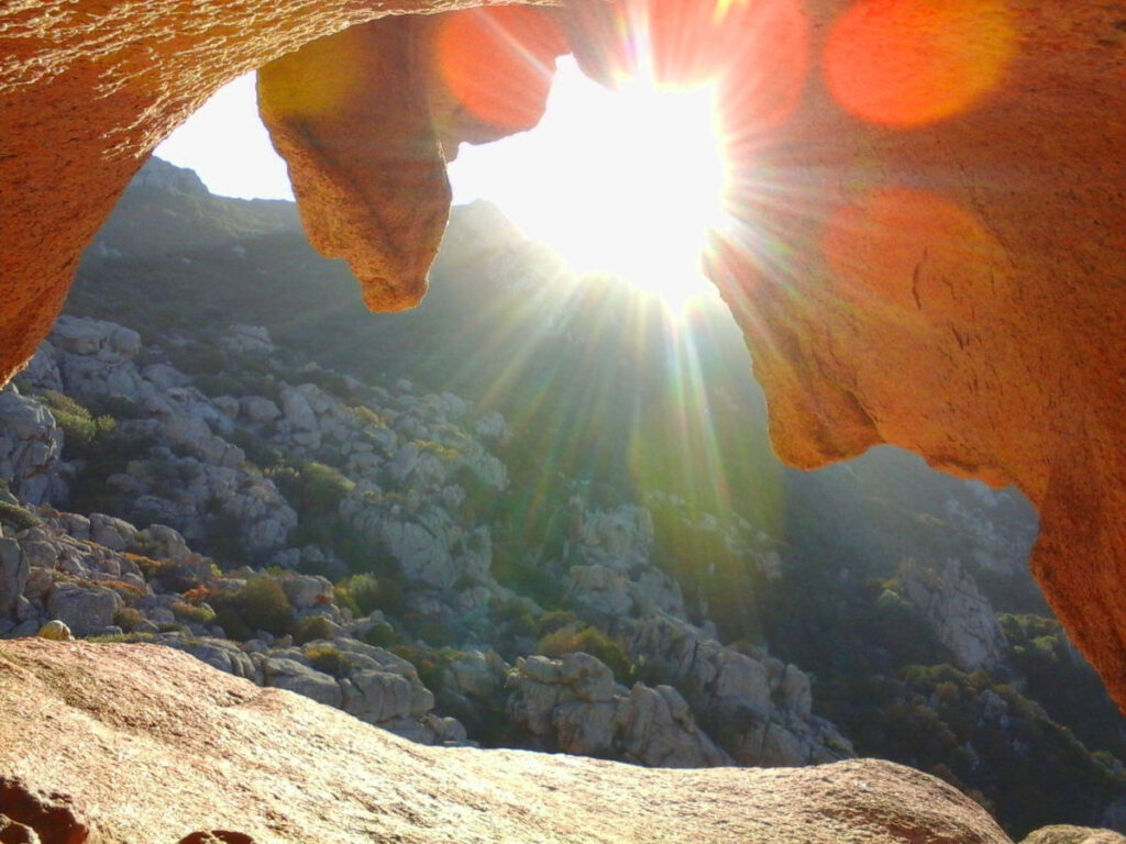 Tiefstehende Sonne scheint zwischen Granitfelsen und erhellt die umliegende Landschaft.