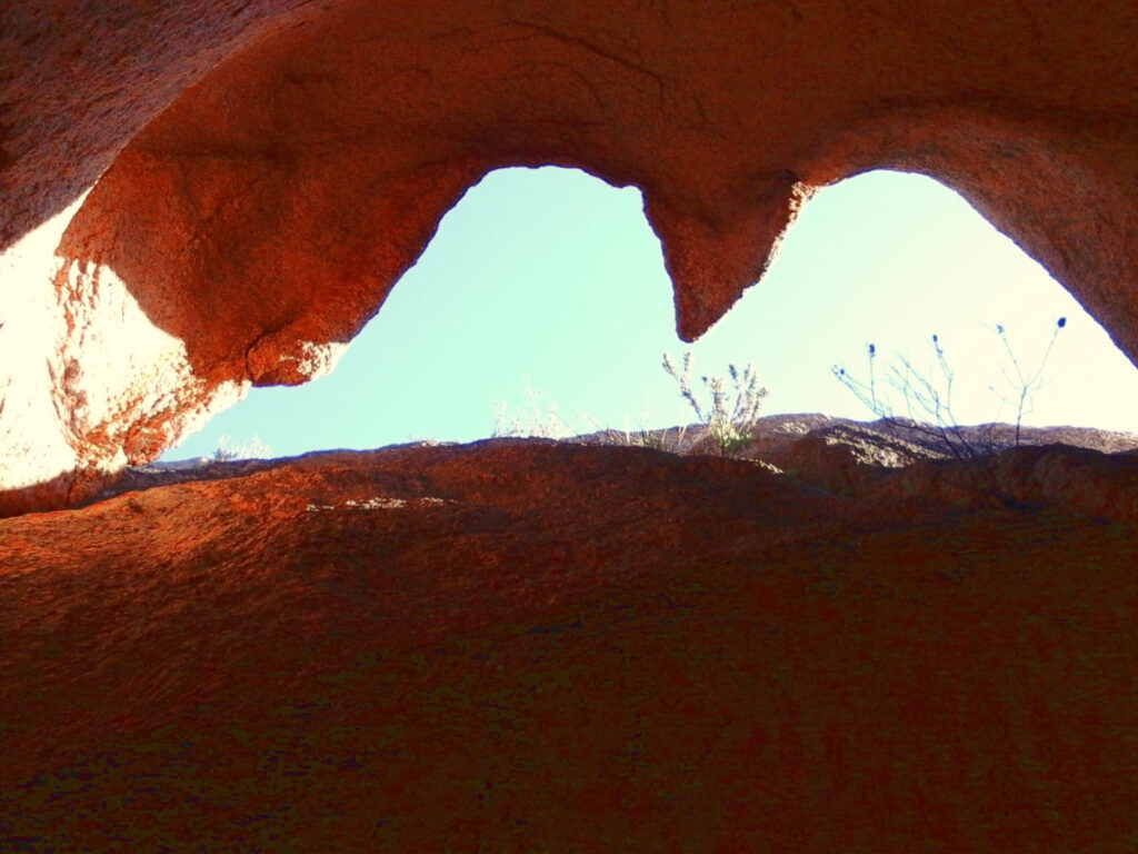 Blick durch eine organisch geformte Felsöffnung ins Licht.